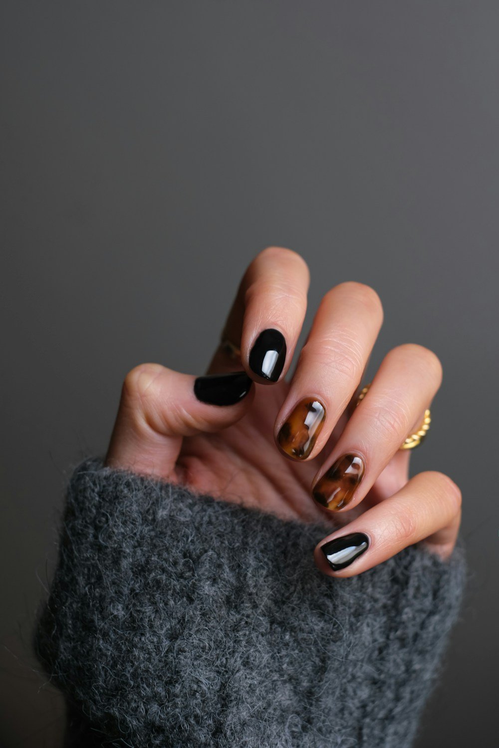 Black and tortoiseshell nails with a gold ring
